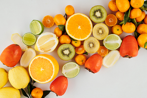 Pile of juicy green and orange ripe fruits like kiwi, oranges, limes and lemos with madnarines