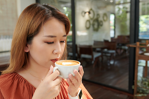 Young woman enjoying cup of tasty coffee in the morning