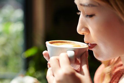 Cropped image of woman enjoying fist sip of coffee in the morning