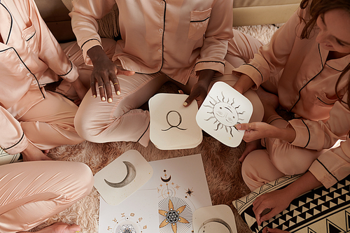 Woman explaining how astrology birth chart works to her friends at pajamas party