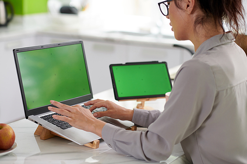 Cropped shot of young female freelancer sitting in front of green screen of laptop and working over new mobile application