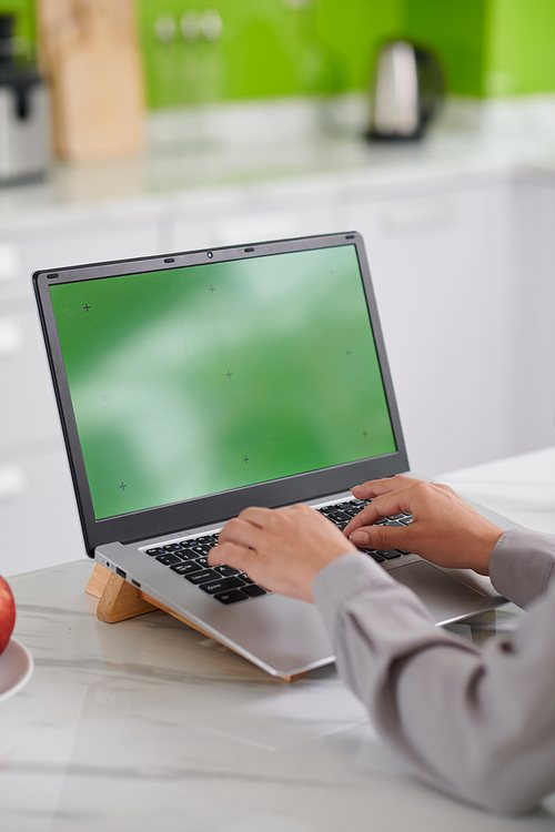 Green screen of laptop and hands of modern freelancer or creative designer over keypad during work over new mobile application