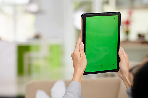 Selective focus on tablet with blank green screen and hands of woman sitting in front of camera and using new mobile application
