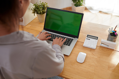 Young businesswoman or freelancer typing on keypad of laptop with blank green screen while using new mobile application