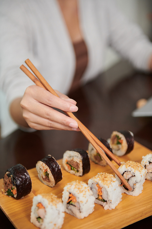 Closeup image of woman eating delicious sushi for lunch in restaurant