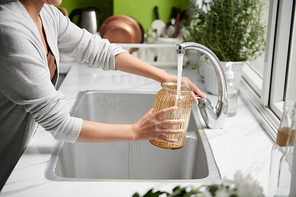 Cropped image of woman filling vase with tap water