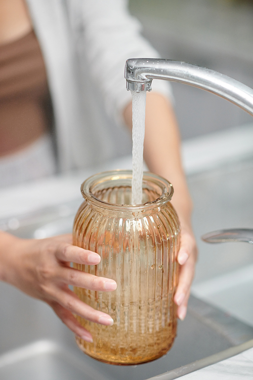 Close-up image of woman pouring fresh water in glass vase