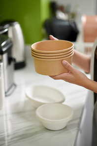 Hands of woman holding stack of biogradable soup bowls