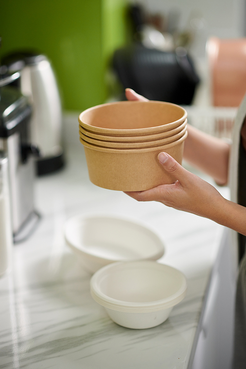 Hands of woman holding stack of biogradable soup bowls