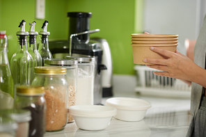 Cropped image of young woman putting breakfast in disposable bowl