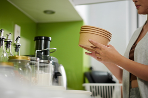 Woman taking out disposable bowls to serve breakfast oatmeal or muesli
