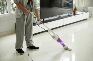 Woman vacuum cleaning tile floor in living room with steam mop