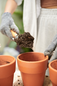 Woman filling flower pots with potting soil