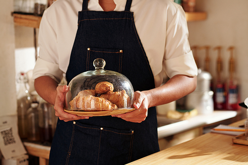 Cropped image of barista holding big plate with fresh pastry