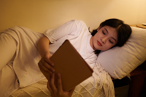 Teenage girl reading e-book in bed late at night