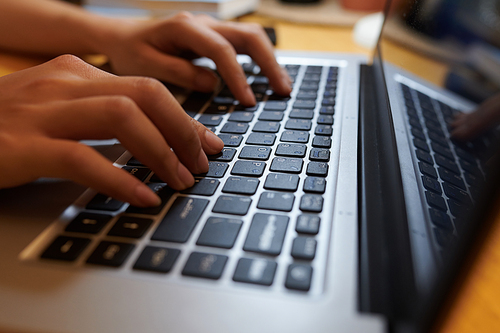 Closeup image of teenage girl coding on laptop at home