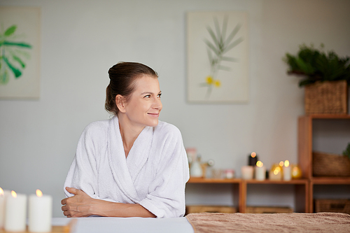 Smiling woman in soft bath towel enjoying spending weekend in spa salon