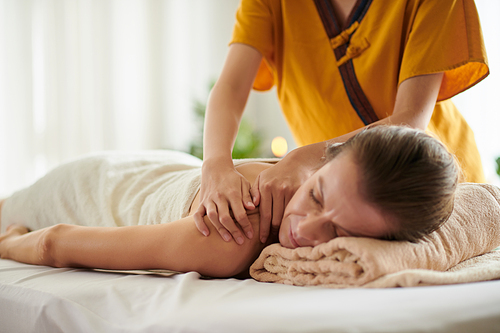 Middle-aged woman getting relaxing back massage in spa salon