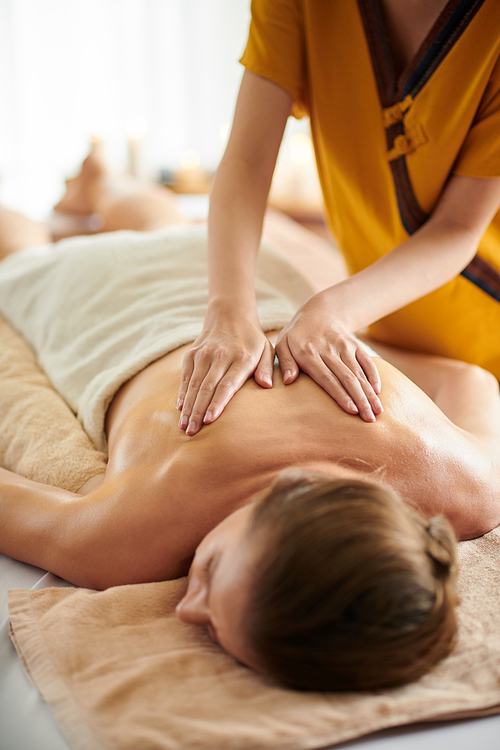 Cropped image of woman getting back massage with oils in beauty salon