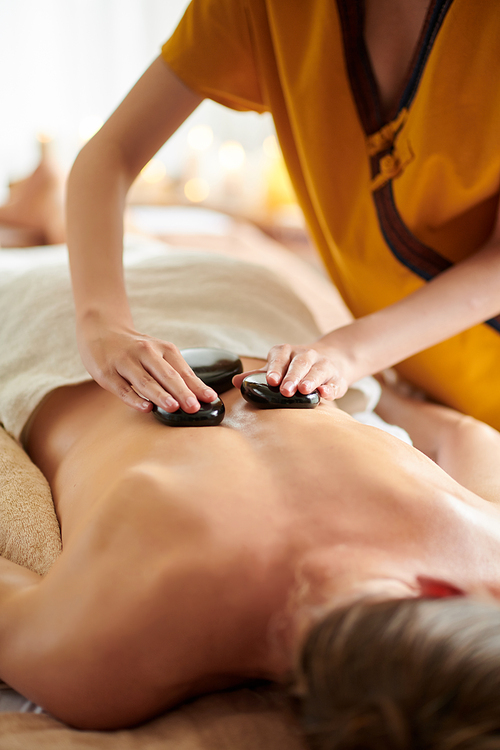 Cropped image of woman getting stone massage in spa salon