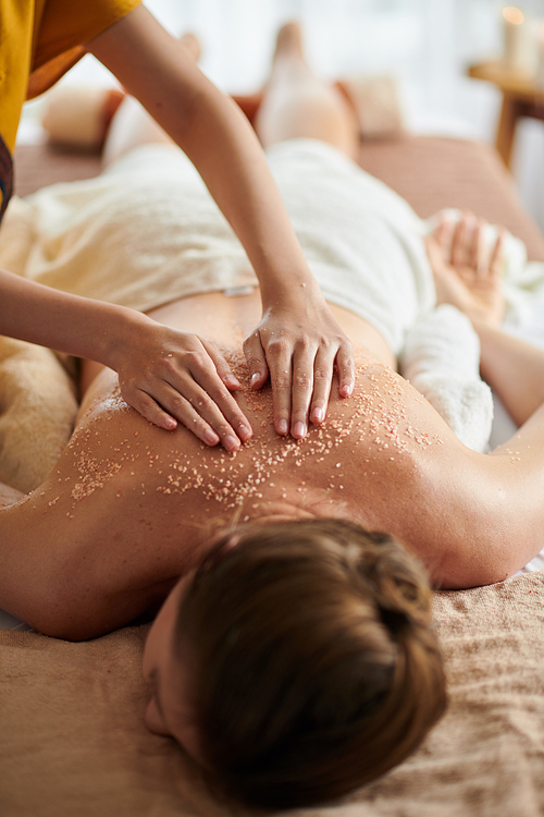 Woman getting deluxe spa treatment including warm seed oil and sea salt scrub