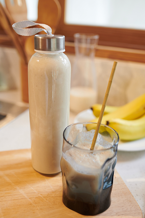 Bottle and glass with protein milkshake on kitchen counter