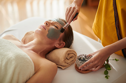 Closeup image of middle-aged woman getting sea minerals mud mask trearment in spa salon