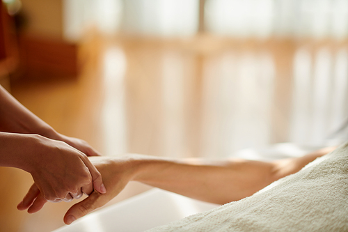 Masseuse massaging hand of female client to release stress and anxiety