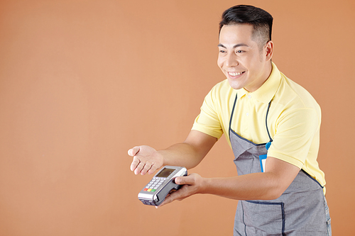 Cheerful coffeeshop waiter giving credit card reader to customer and accepting payment