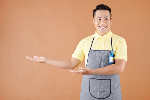 Portrait of smiling Asian hospitable waiter welcoming customers in coffeeshop or cafe