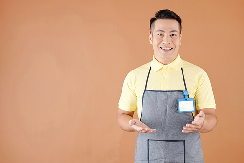 Studio portrait of cheerful talking Vietnamese cafe waiter or coffeeshop barista