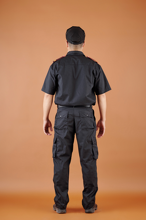 Confident security guard in black uniform, view from the back
