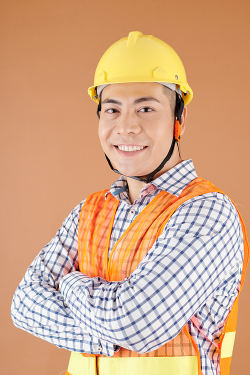 Studio portrait of smiling confident civil engineer in hardhat crossing arms and looking at camera