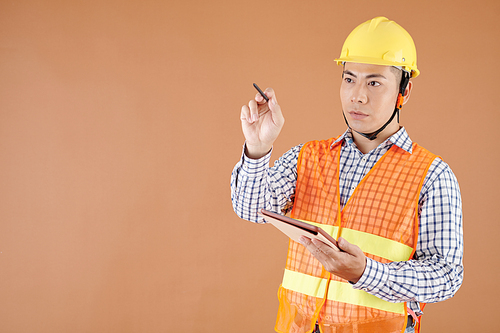 Portrait of construction engineer with tablet computer drawing in the air with digital pen