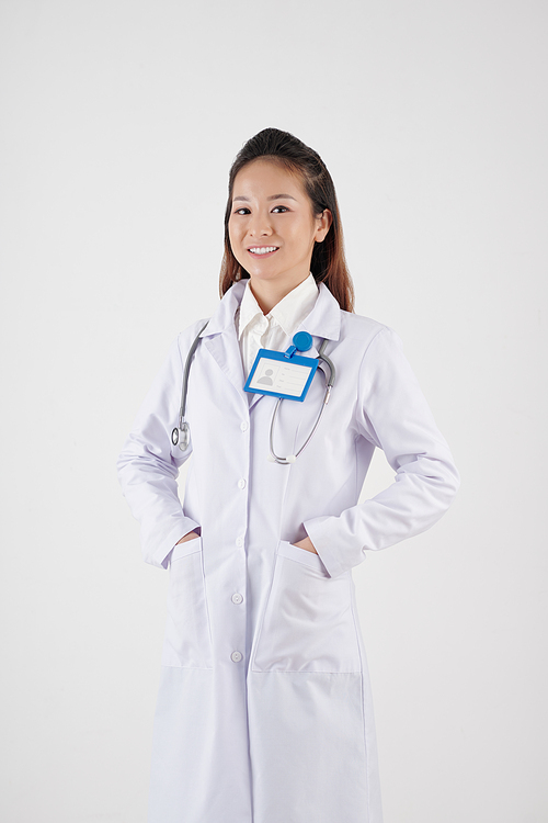 Studio portrait of young female general practitioner in labcoat smiling at camera