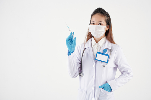Young female doctor in medical mask holding syringe with vaccine against coronavirus, isolated on white