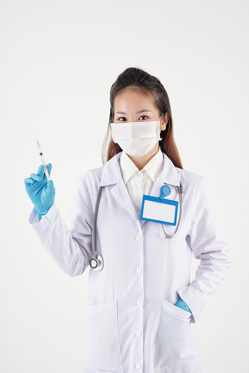 Studio portrait of doctor in white labcoat and stethoscope holding syringe