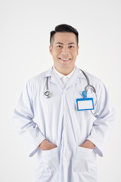 Portrait of smiling Asian general practitioner putting hands in pockets of his labcoat