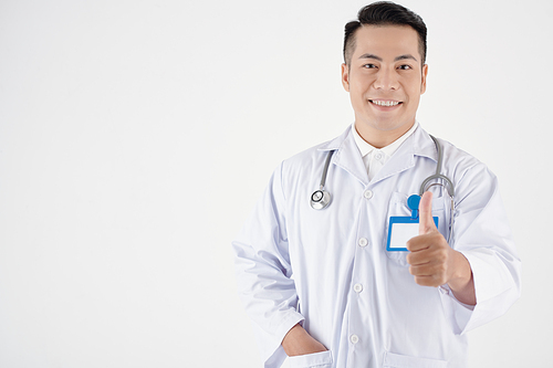 Portrait of smiling general practitioner showing thumbs-up, isolated on white