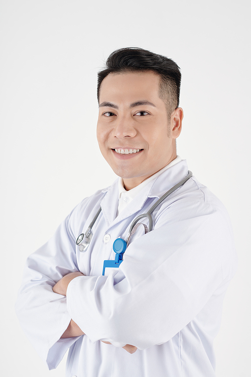Studio portrait of happy Asian physician crossing arms and looking at camera