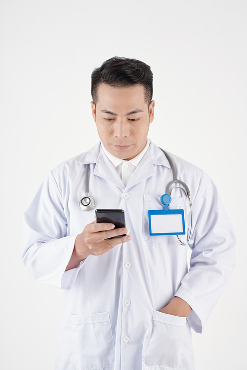 General practitioner in labcoat checking notifications on smartphone