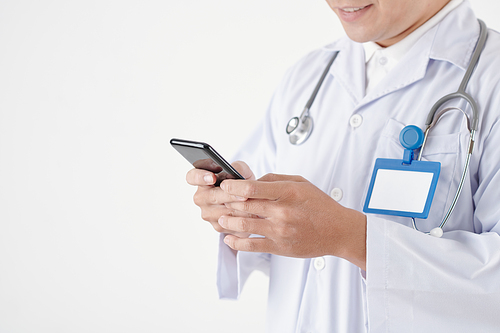 Close-up image of doctor answering text messages of patient on smartphone