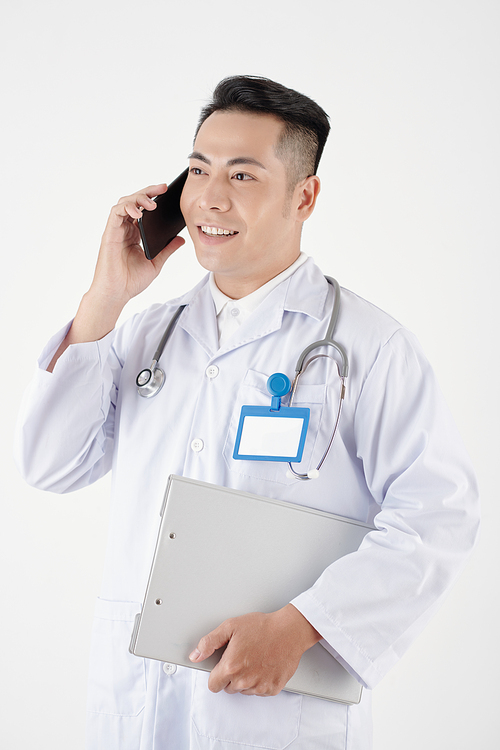 Portrait of positive physician holding medical history and talking on phone with patient or colleague
