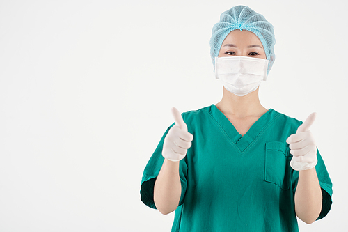 Portrait of happy nurse in protective mask showing thumbs-up with both hands