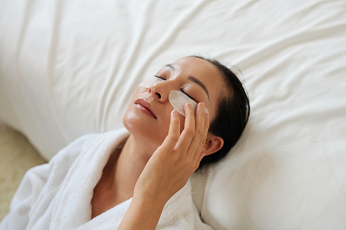 Young woman applying undereye patches to get rid of morning puffiness