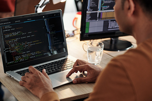 Software developer coding on laptop and reviewing code for mistakes