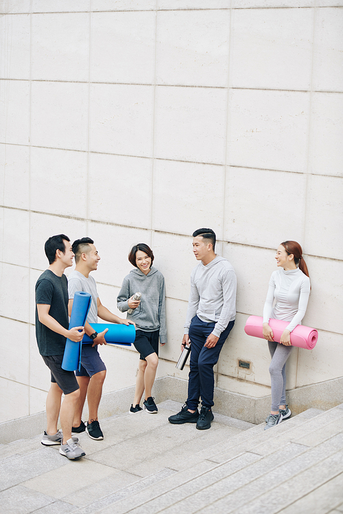 Young Asian people standing outdoors and discussing yoga training they had