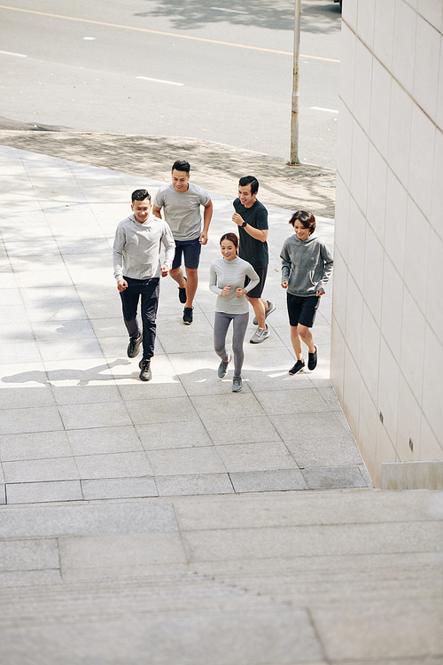 Young smiling Vietnamese men and women jogging in city early in the morning