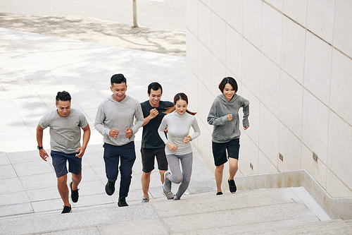 Fit smiling young Asian people running up the stairs when training for marathon in the morning