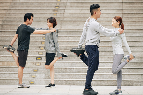 Fit smiling young people working out in pairs after jogging in the morning